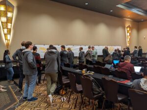 Big Picture EventStorming in action: People having conversations and placing sticky notes on butcher paper hanging on a wall